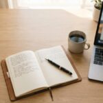 An organised writing desk with an open notebook, pen, coffee and laptop, representing a monthly blogging service