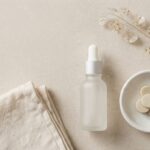 Flat-lay of minimalist unbranded skincare products on a neutral stone surface, representing a curated beauty Shopify store