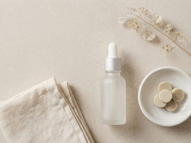 Flat-lay of minimalist unbranded skincare products on a neutral stone surface, representing a curated beauty Shopify store